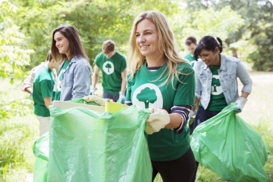 Charity volunteers in matching T-shirts collecting litter in a park