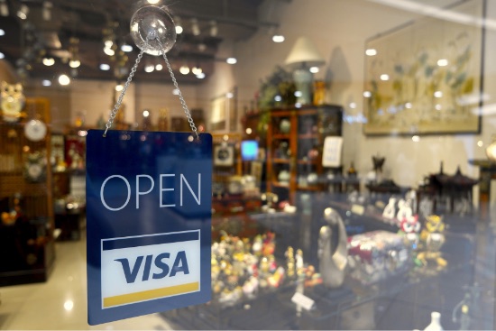 An open sign and a Visa sticker on a shop door